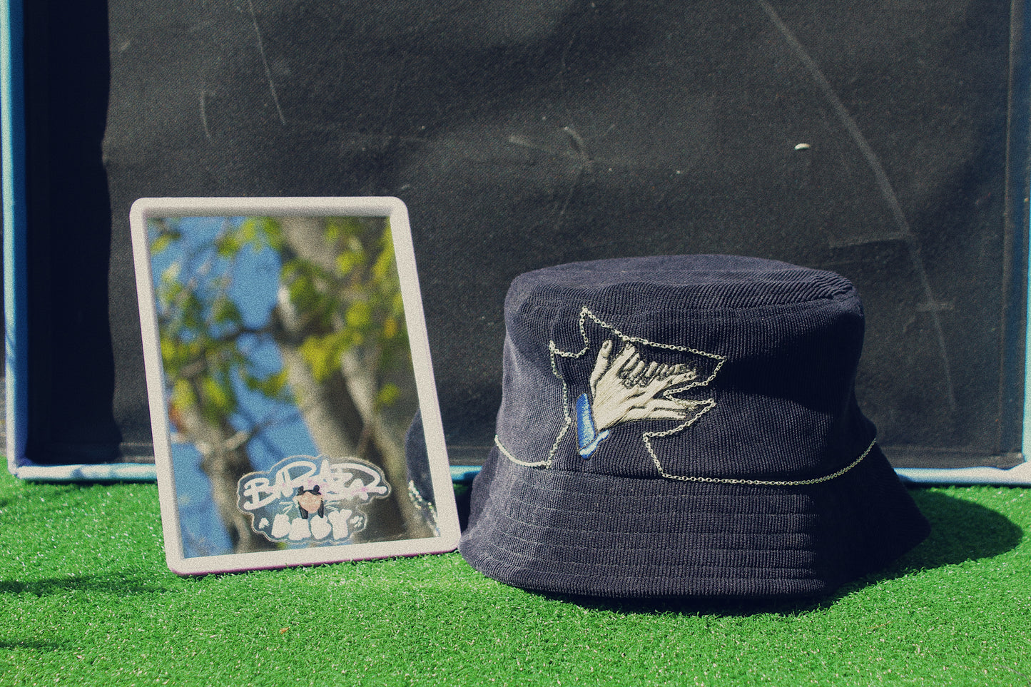 black megumi hat sitting next to mirror on fake grass